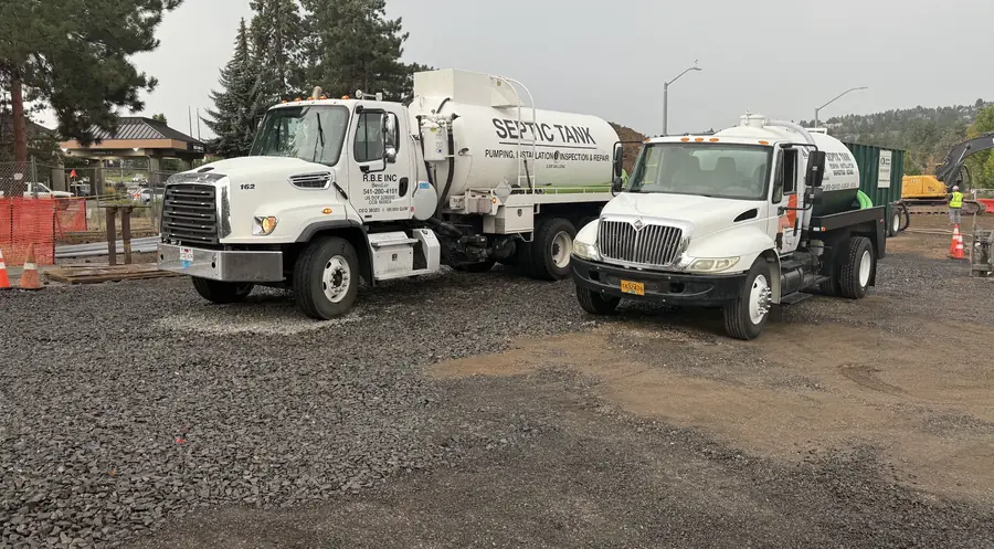 Both RBE Inc. septic trucks parked side by side on a gravel lot at a Bend, Oregon job site