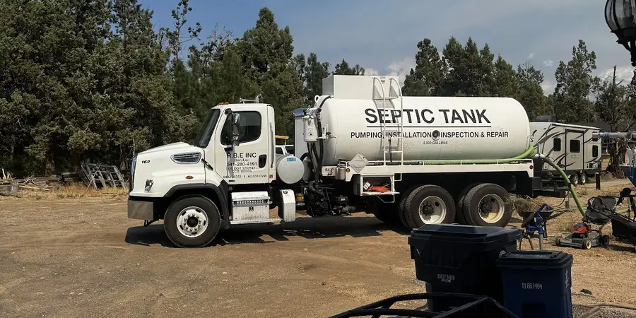 RBE Inc. septic tank truck on a gravel job site among juniper trees in Central Oregon